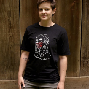 A person wears a black t-shirt, with a graphic design of a woman with a red hand covering her lips.
